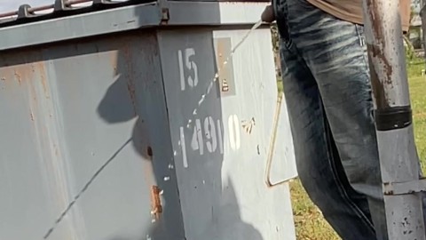 Tirando jarras de té vacías en un contenedor de basura orina pública desesperada al aire libre cerca de los vecinos